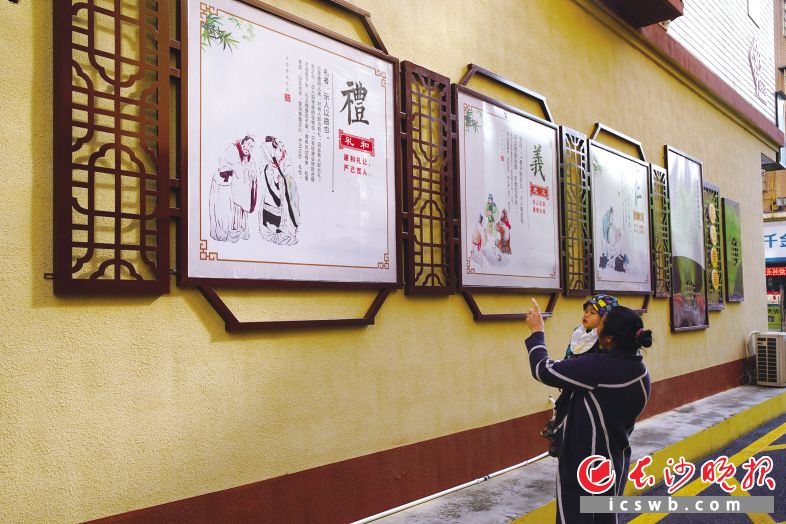 　　在长沙县泉塘街道泉星社区安置区，居民陈倩娣带着孙子观看文明标语，并教孙子读“礼”字。彭家瑞 摄
