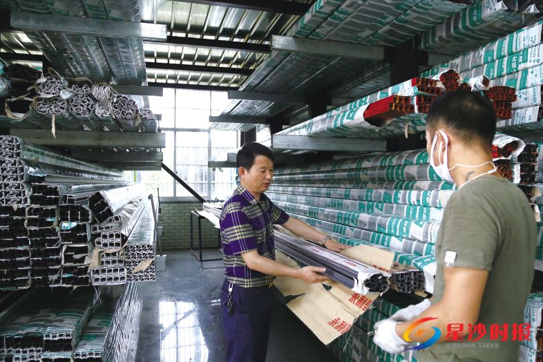 　　曹新忠(左)在厂房中查看两种包装材料的区别，致力于推动全省铝型材外包装新标准出台。　　刘丹青 摄