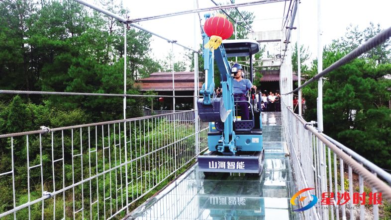 　　近日，一台重达3吨的山河智能SWE18UB微型挖掘机，在岳阳平江石牛寨180米的全透明高空玻璃桥上演惊险一幕：经过一番艰难前行，这台“重量级嘉宾”在众人的围观下成功登上玻璃桥，并在玻璃桥上来回碾压，进行安全测试。　　最终结果显示，桥面玻璃虽不可避免地出现了一定程度的划痕和刮伤，但却丝毫没有碎裂的迹象，证实了石牛寨玻璃桥具有较高的安全性能。在打消游客安全顾虑之余，这台SWE18UB微型挖掘机也凭借它的出色表现赢得了现场观众的热烈掌声。　　据了解，山河智能SWE系列微型液压挖掘机，因具有精致、可爱的外观以及可靠、灵活的整体操作性能，被广大用户亲切地称为“施工小精灵”！产经周刊记者 蒋炼 摄影报