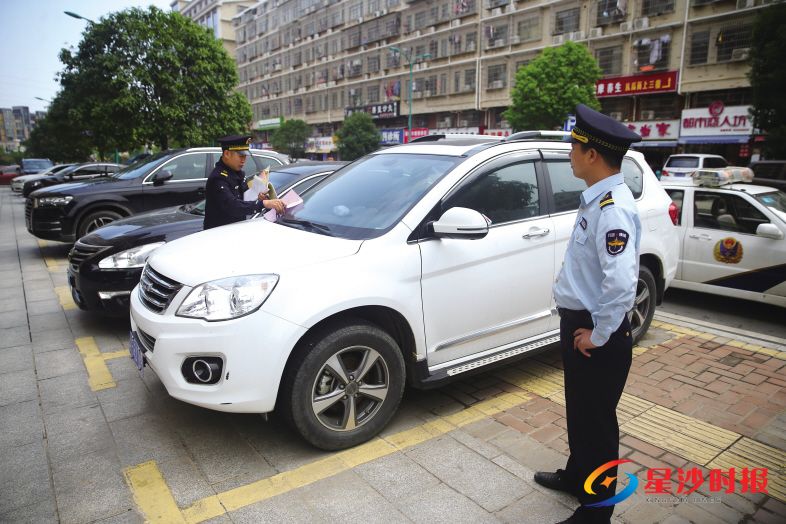 昨日,位于长沙县湘龙街道龙塘路的亿天大酒店擅自占用盲道施划停车位,执法队员依法一一开具罚单。 盛磊 摄