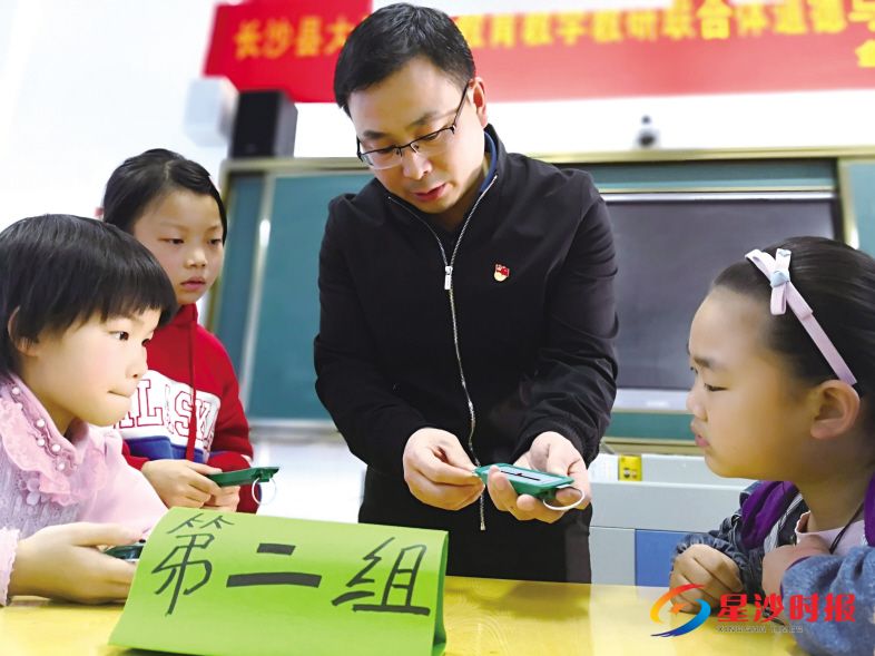　　双江中心小学校长常记在科学课上指导学生使用仪器测量力的大小。潘东晓 摄