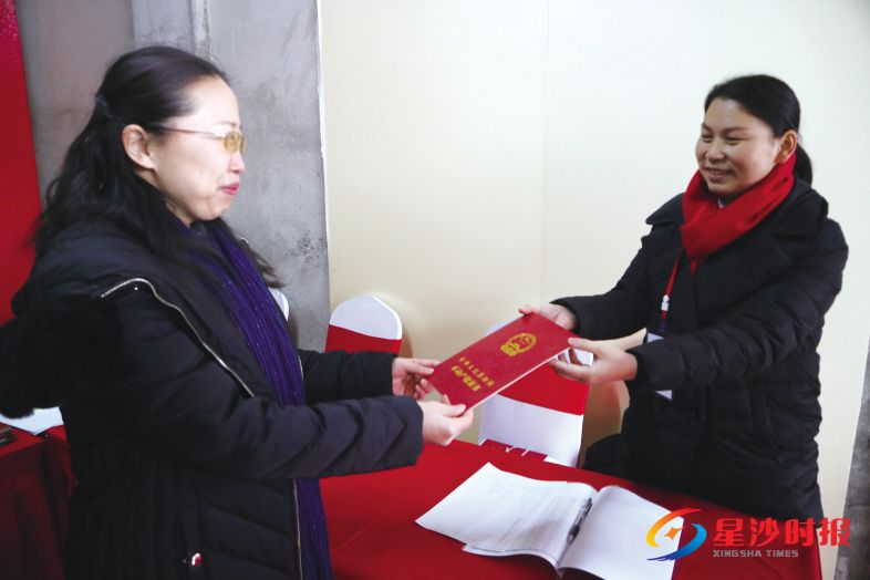 　　2018年12月30日上午9时许，刚从开发商手中拿到新房钥匙的星湖湾小区业主何英（左），马上领到了不动产权证。罗展 摄