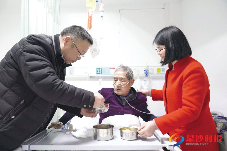 　　十年前彭昕在湘江边上与周海良老人一见如故，将老人当作父亲一般照顾了十年，如今他们的“父子”情缘还将一直延续下去。图为彭昕（左）和妻子杨新元（右）正在喂周爹喝汤。　　章帝 摄