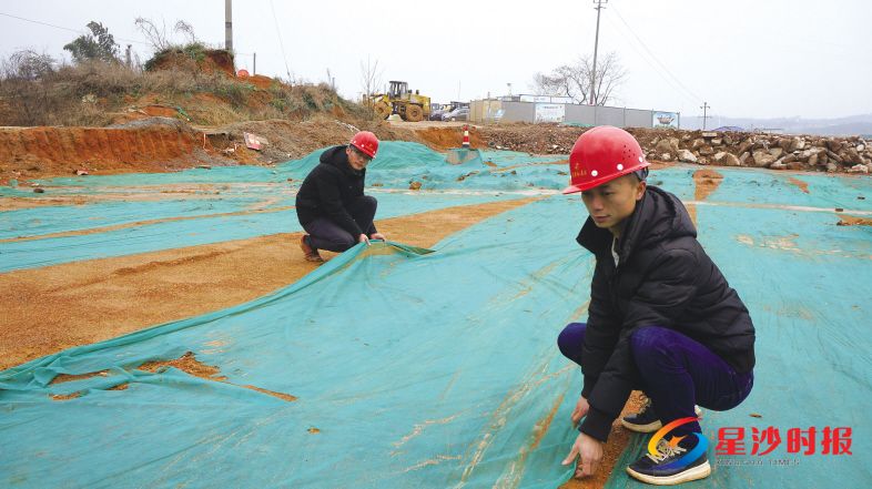 绿野路道路工程复工后,工人们将停工期间被风刮乱的绿布进行重新覆盖。彭帅 摄