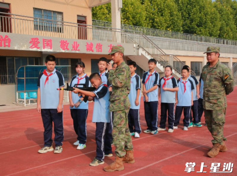 在长沙县特立中学，教官们指导学生使用仿真武器。县发改局供图