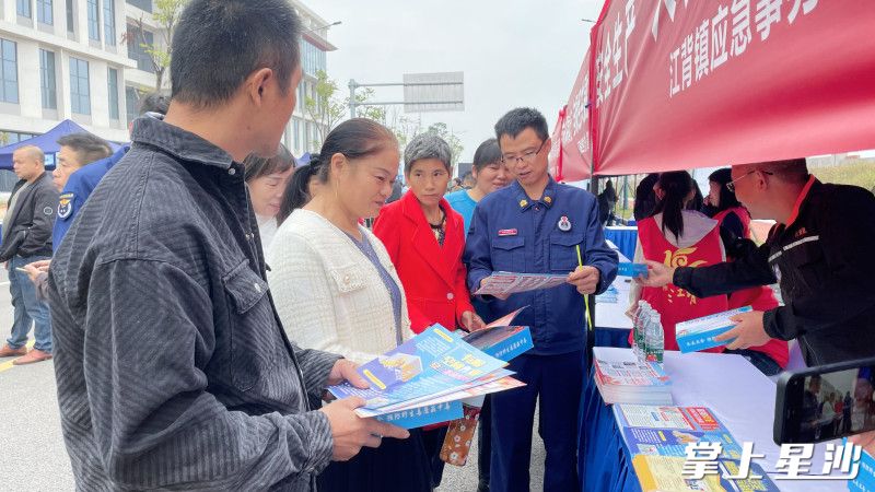 工作人员向求职者发放安全生产法律法规、消防安全、电气安全等实用知识的宣传手册。均为江背镇供图