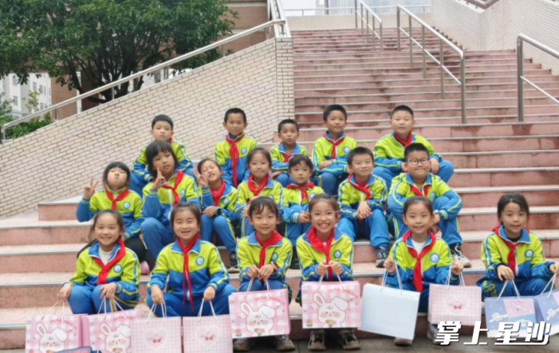 孩子们将“爱心礼包”送到学校接收点。