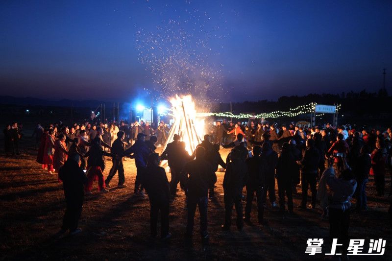 长沙县金井镇龙华山村龙华山滑翔伞基地热闹非凡，举办的“一日村厨”活动持续至夜晚，罗雨林和村民们一起在篝火旁舞蹈。均为金井镇供图