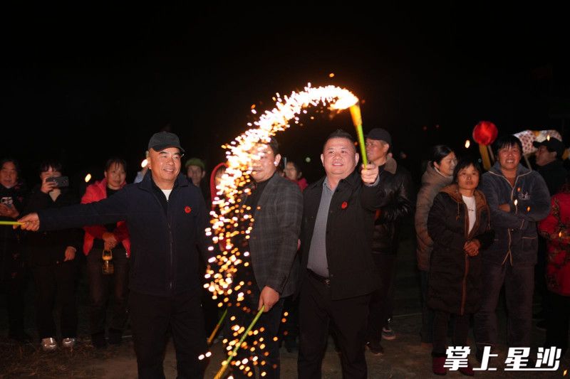罗雨林（右一手持烟花）与村民一起玩烟花。