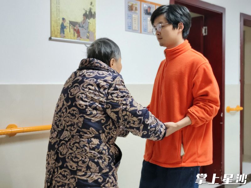 护理员林悦峰带着老人散步 。长沙县民政局供图