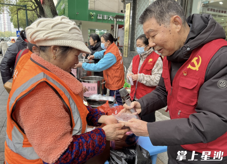 社区工作人员把暖暖的腊八粥送到环卫工人手中。通讯员供图