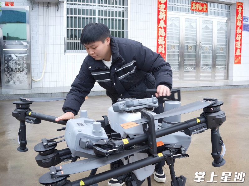 长沙县金井镇思斯家庭农场负责人杨思斯正操作植保无人机准备播撒肥料。 长沙县金井镇思斯家庭农场负责人杨思斯正操作植保无人机准备播撒肥料。