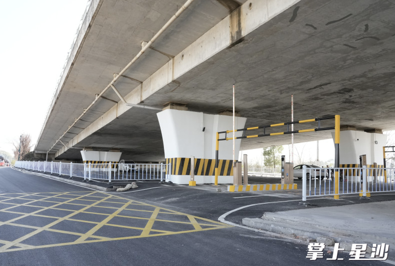 桥下停车场焕然一新：沥青路面平整干净，配备了照明灯、监控摄像头、道闸、限高栏和围栏等设施。