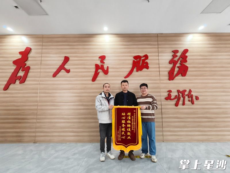 长沙星朝汽车有限公司人力资源部部长易泽国（左一），将一面印有“精准招聘促就业 贴心服务暖民心”的锦旗郑重交到街道工作人员手中。 街道供图