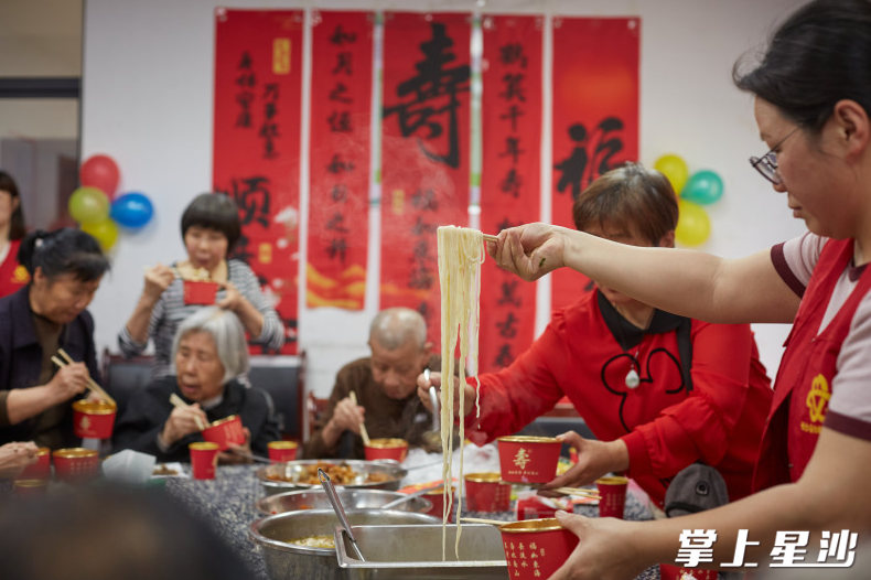 志愿者为老人们端上长寿面。