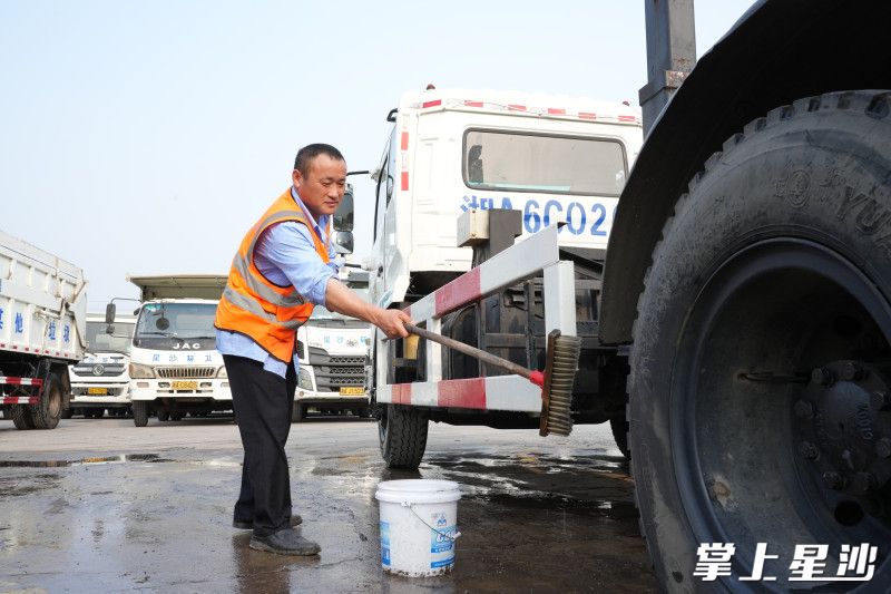 环卫工人张明正在用刷子刷去顽固污渍。