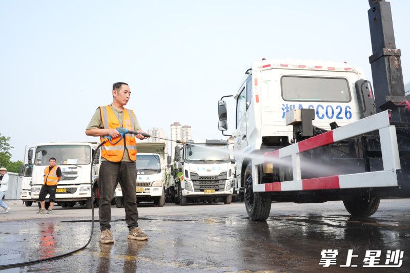 环卫工人李力正在用高压水枪冲洗车架。