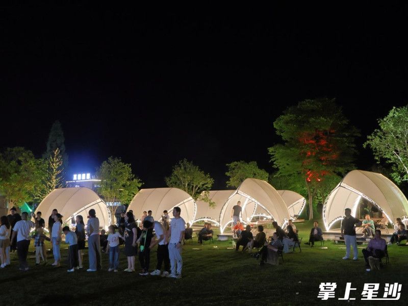 星空露营区，游客在帐篷周围嬉笑欢聚。