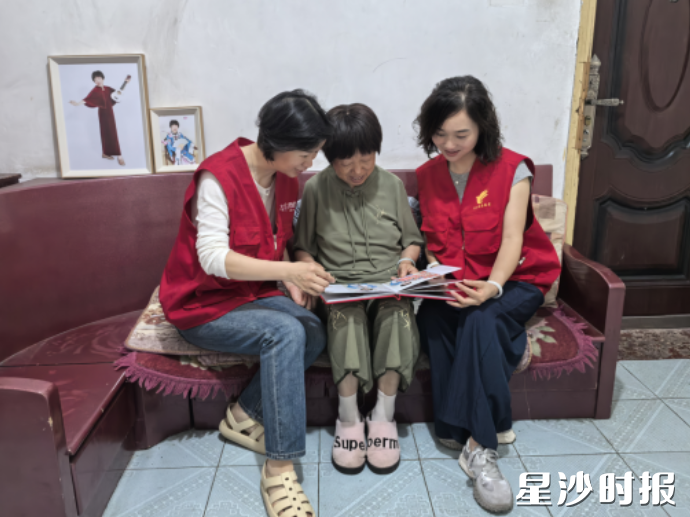 志愿者和老人一起翻看新相册。街道供图 