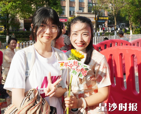 长沙市弘益高级中学考点，陪考家长送孩子到达后收到志愿者赠送的鲜花。彭福宗 摄