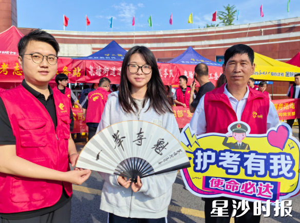 长沙县第一中学考点，志愿者为考生送上精心定制的折扇。郭银 摄