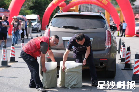 在长沙市明达中学考点，黄兴镇蓝田新村志愿者搬来冰块，为守候的家长和执勤的交警降温解暑。