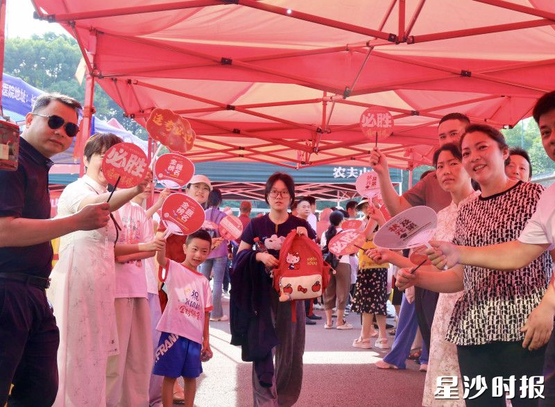 在长沙县第一中学考点，家长挥舞“必胜”扇，为考生加油。文雅丽 摄