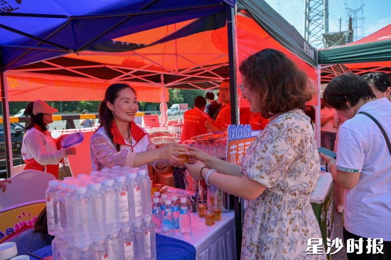 志愿者将矿泉水递到家长手中。长沙县志愿服务联合会供图