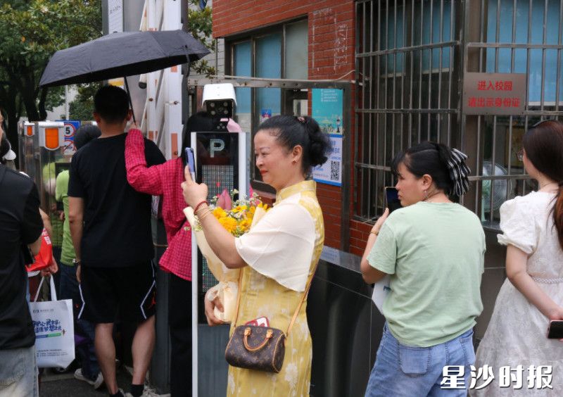 家长身穿旗袍，手持鲜花等待考生归来。