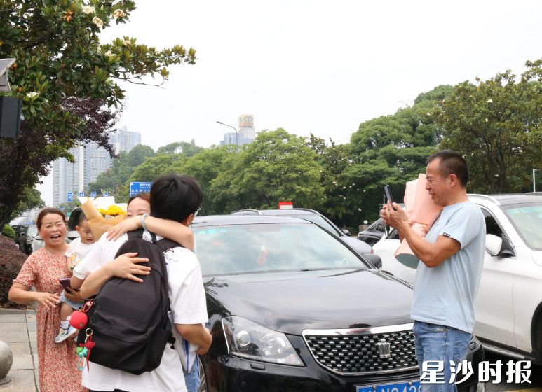 考完的考生与母亲紧紧拥抱，父亲用手机记录这一幕。