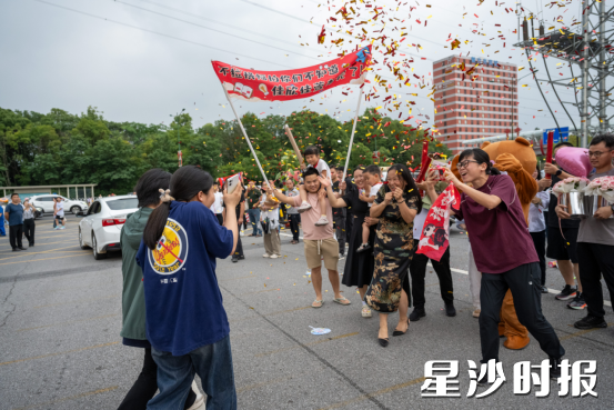 长沙县一中考点，一场精心策划的“惊喜”正在上演。为了迎接刚刚结束高考的双胞胎女儿，一位妈妈集结了一支十余人的“豪华亲友团”。只见姨妈套上了厚重的毛绒兔玩偶服，化身一只憨态可掬的大兔子；其他成员则各司其职——拉横幅、备香槟、握礼花筒、怀抱鲜花，严阵以待。终于，校门开启，熟悉的身影冲出考场！女儿们望见这盛大的阵仗，飞奔向母亲的那一刻，妈妈再也抑制不住翻涌的情绪，泪水瞬间盈满眼眶…… 黄宇 摄