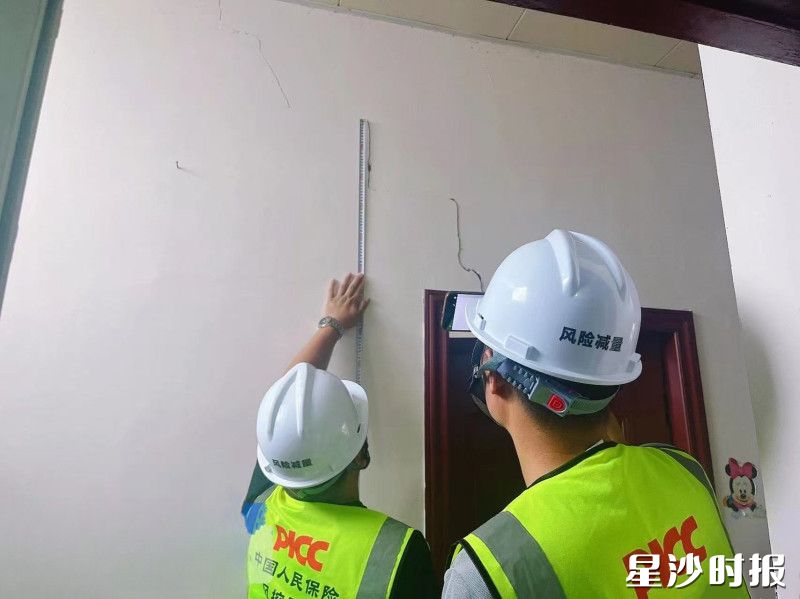 工作人员正在丈量裂缝长度。均县住房城乡建设局供图