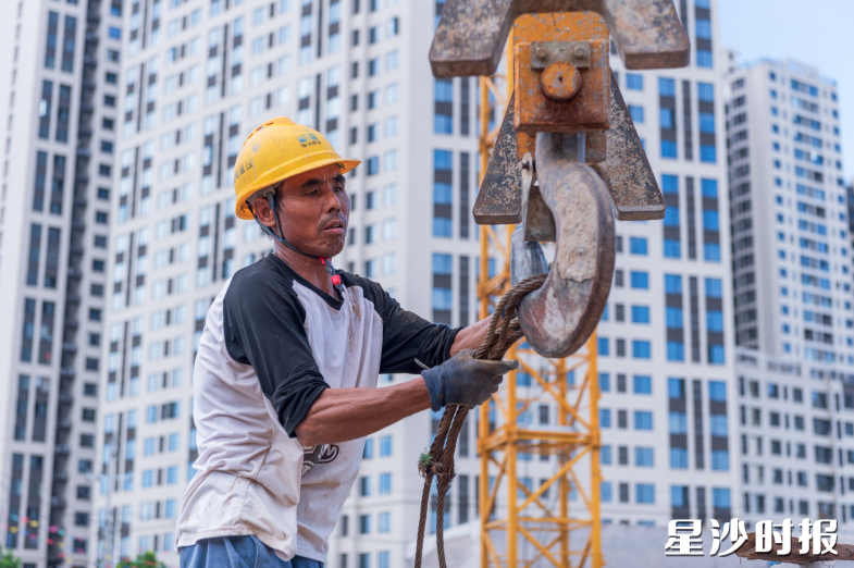 建筑工人把捆扎好的钢筋用绳子挂上吊臂。