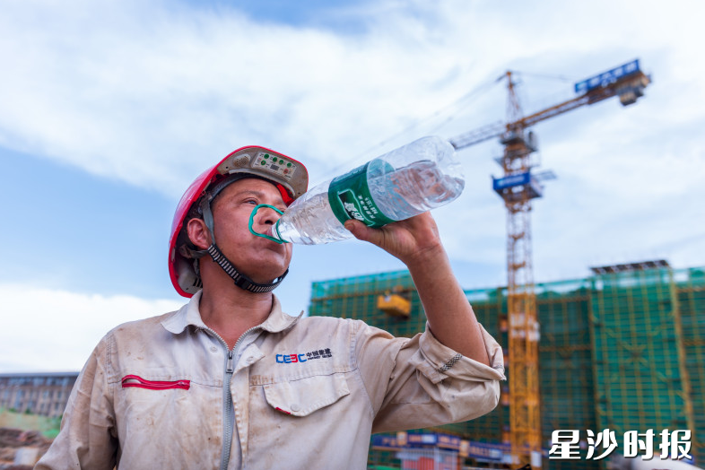 建筑工人大口喝水，补充水分。