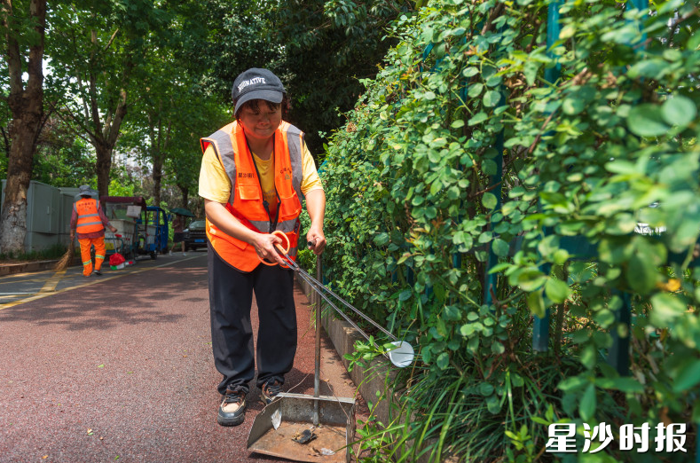环卫工人正在清理绿化带里的垃圾。