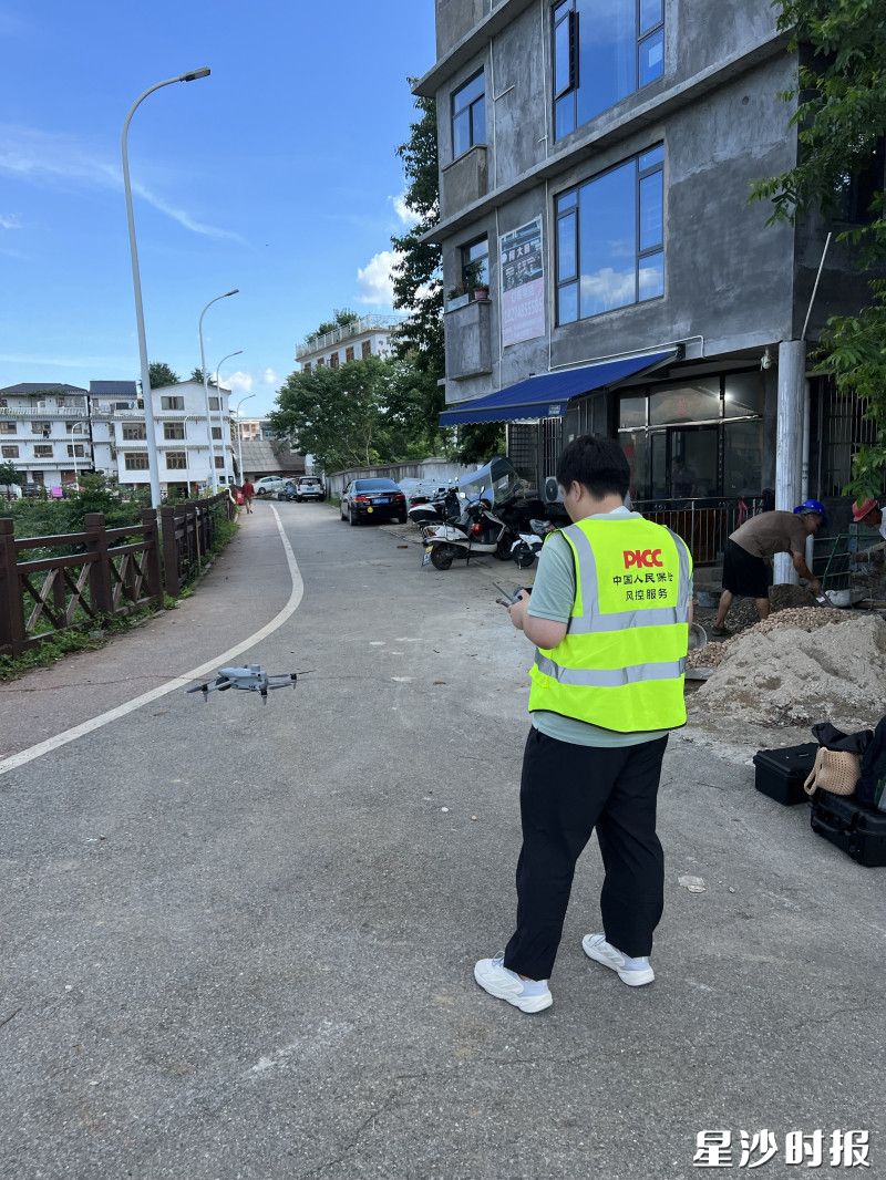 人保巡检人员身着标识背心,操控无人机,对自建房开展“空基巡检”。