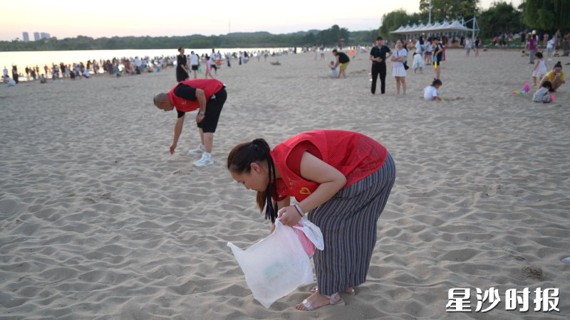 志愿者在湖南松雅湖国家湿地公园沙滩捡拾垃圾。