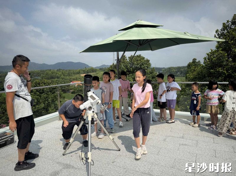 在天文台观测平台，老师指导孩子们小心翼翼调整望远镜角度，观测太阳黑子。