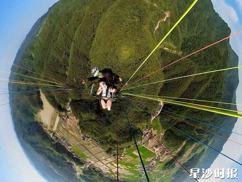 在龙华山国际滑翔伞基地，游客体验滑翔伞，从高空俯瞰，青山绿水尽收眼底，让人心旷神怡。