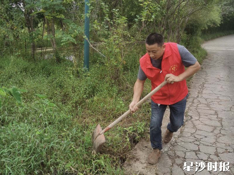 盛夏时节，组级道路杂草疯长，胡海正在清理。安沙镇供图