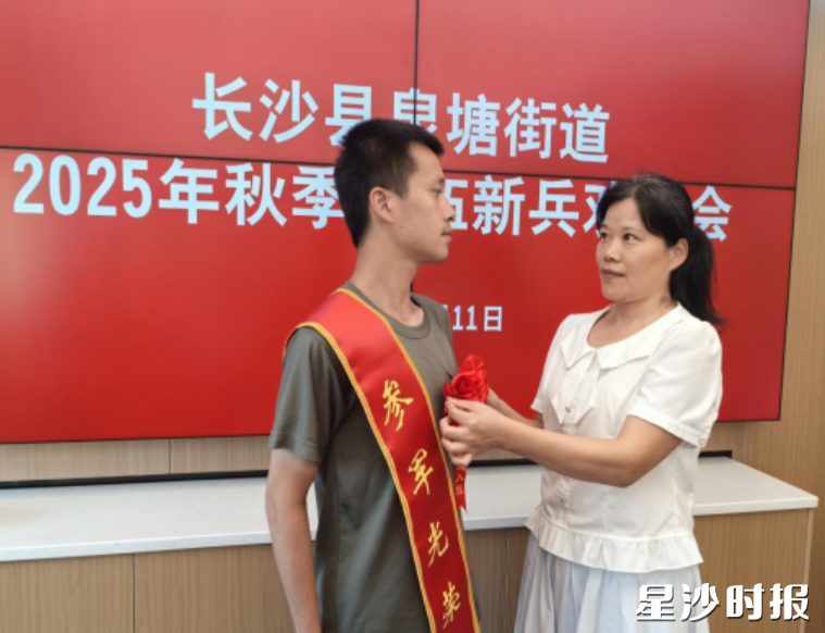 胡浩明妈妈为儿子佩戴大红花。