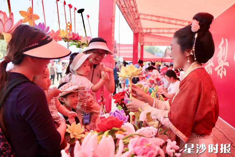 游客们购买欣赏扭扭棒手工花。