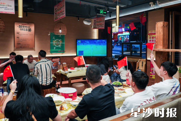 串盟烧烤的几家店铺内氛围浓厚，部分球迷挥舞起国旗为比赛呐喊。