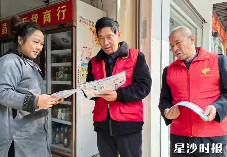 志愿者曹建国（中）、吴正秋向商户发放消防安全宣传折页，上门入户宣讲。