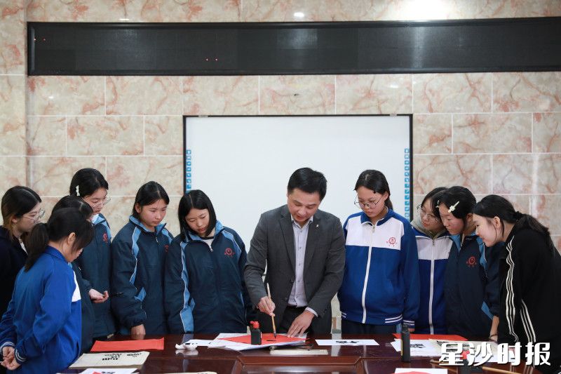 詹习成手持毛笔，现场指导学生们书写“福”字。