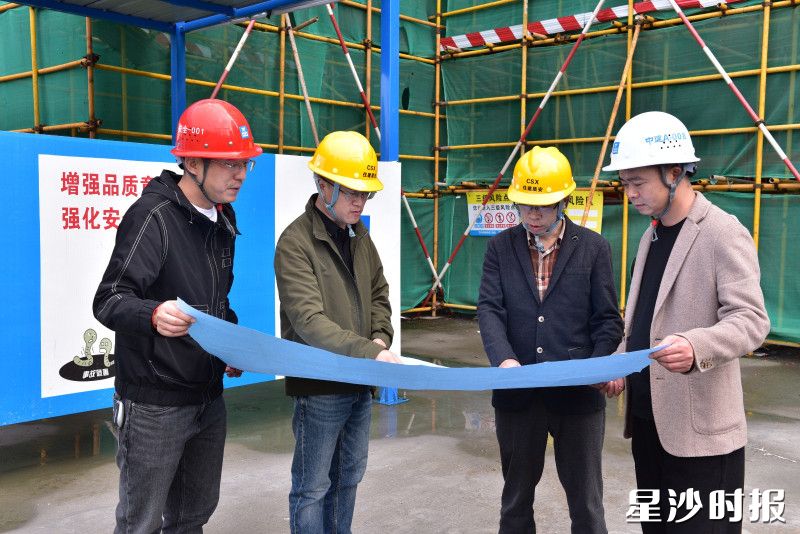 县住房城乡建设局工作人员在建筑工地核对施工图纸。均为刘思源 摄