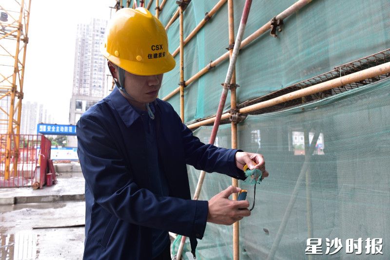 县住房城乡建设局工作人员在建筑工地检查安全网阻燃性能。