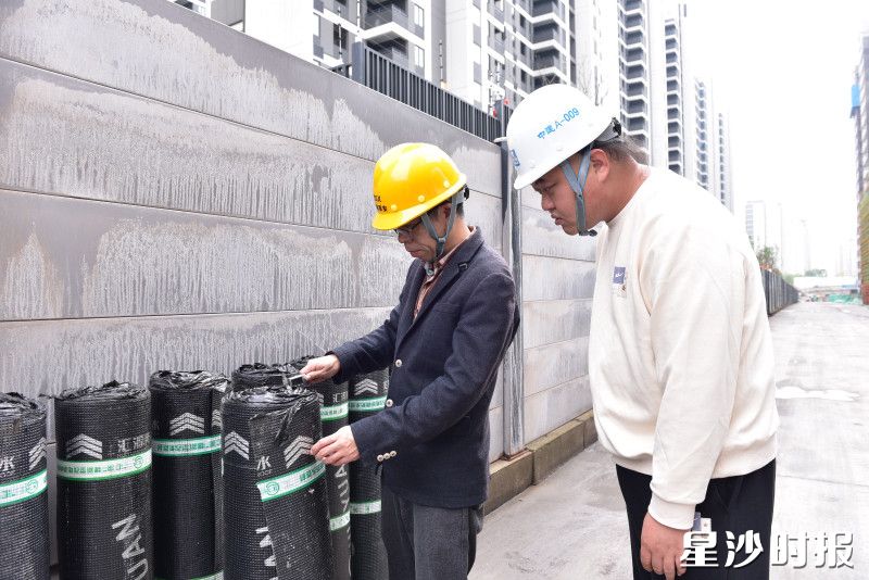 县住房城乡建设局工作人员在建筑工地检查防水卷材。