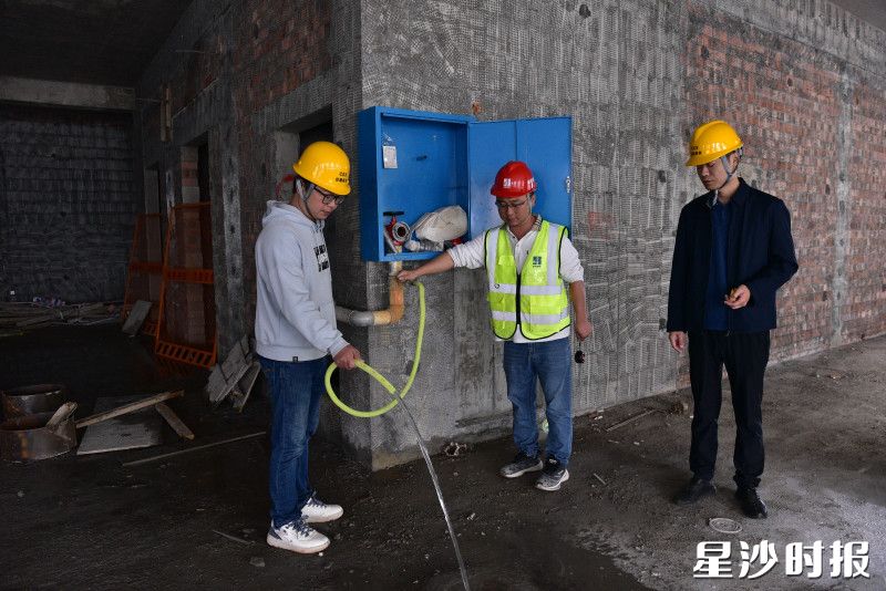 县住房城乡建设局工作人员在建筑工地检查临时消防装置是否能正常使用。
