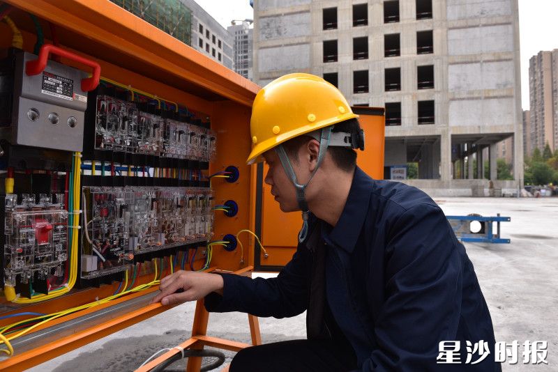 县住房城乡建设局工作人员在建筑工地检查配电箱元器件型号和参数。